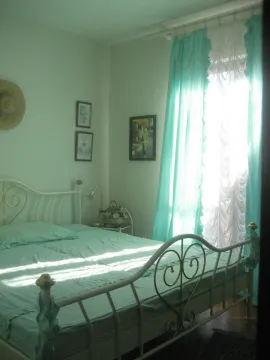 Bedroom with a metal-frame bed and turquoise curtains. - image 3