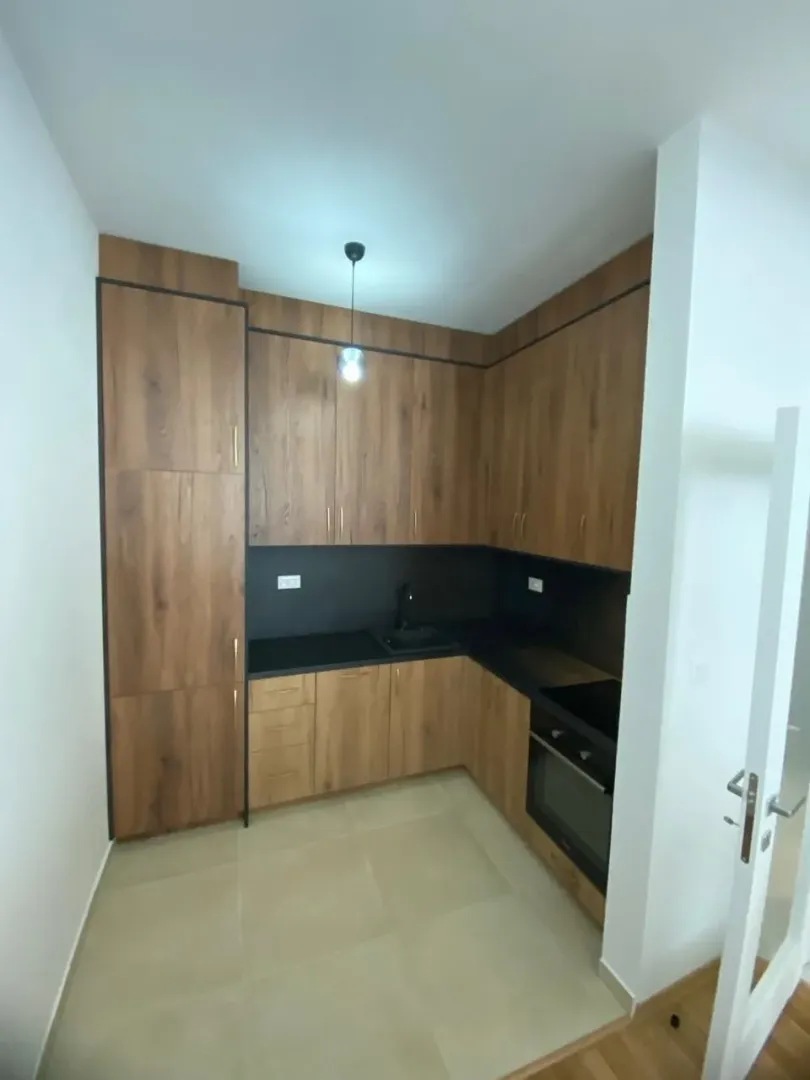 Kitchen in wood tones with a black countertop and built-in appliances.