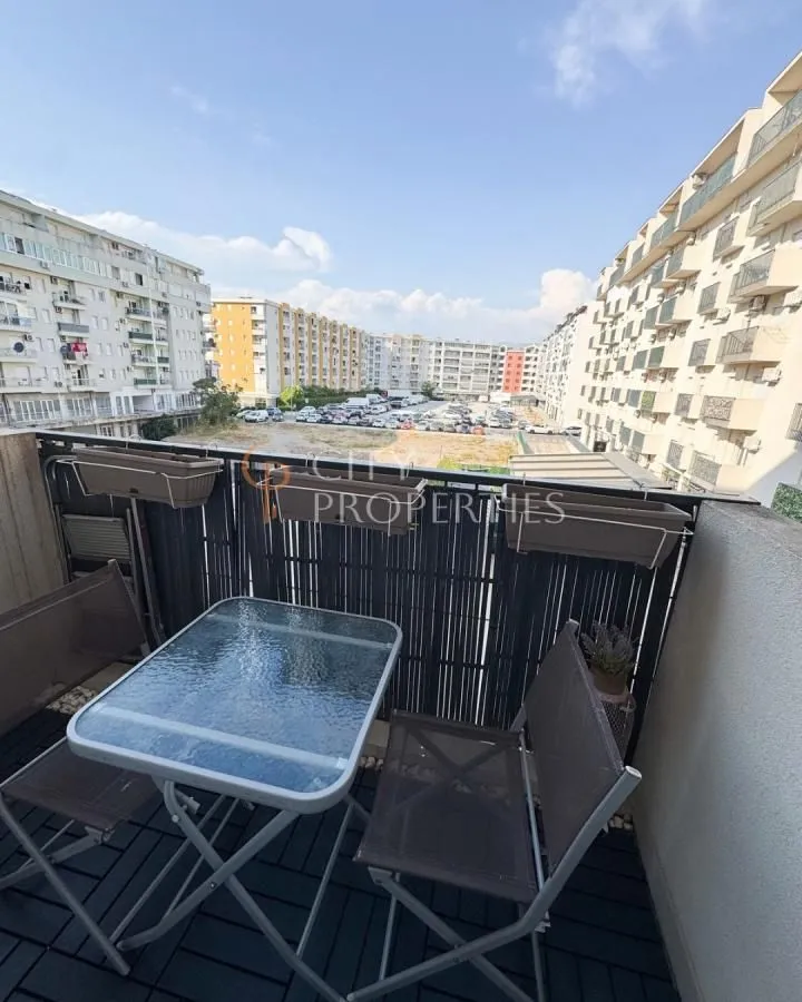 Namješten balkon sa stolom i stolicama i pogledom na naselje.