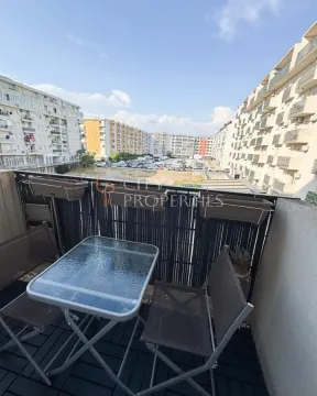Namješten balkon sa stolom i stolicama i pogledom na naselje. - image 6