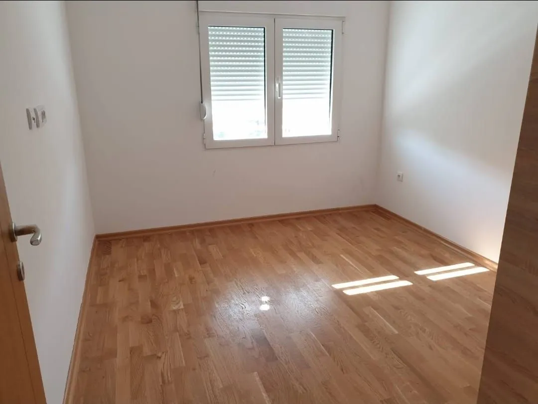 Prazna soba sa parketom i prozorom.