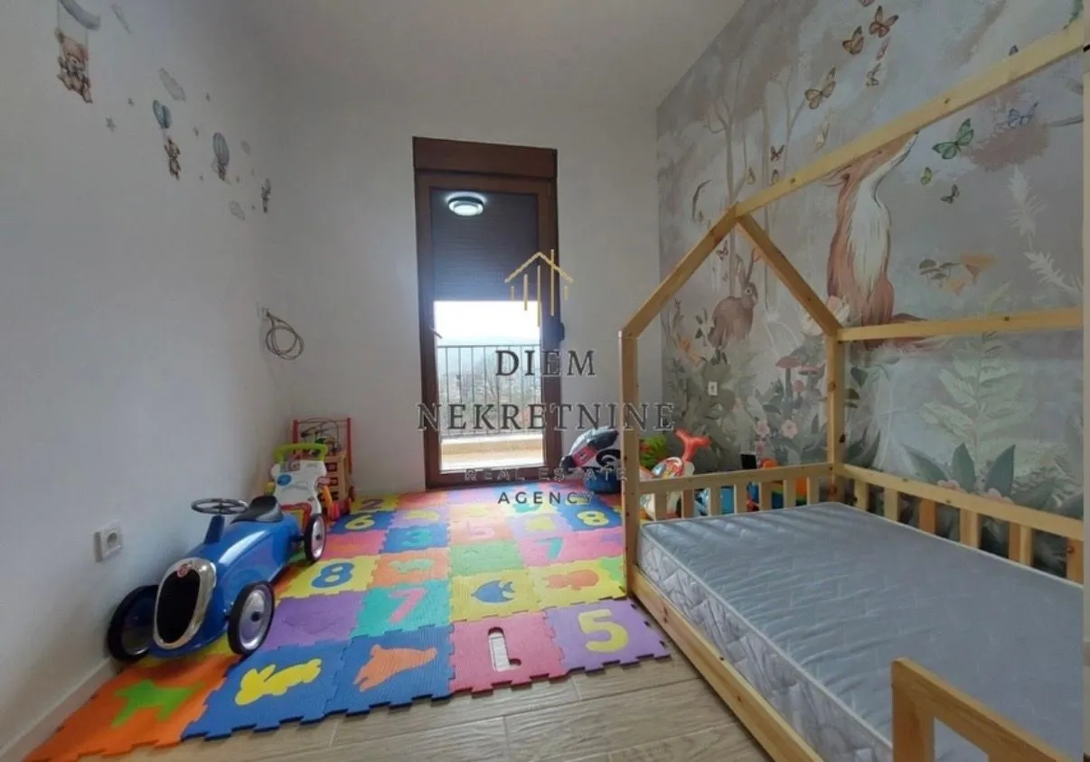 Dječja soba sa drvenim krevetom i šarenom podlogom za igru.