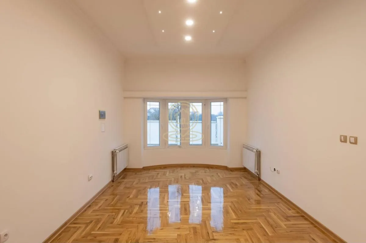 Empty room with parquet flooring and windows.