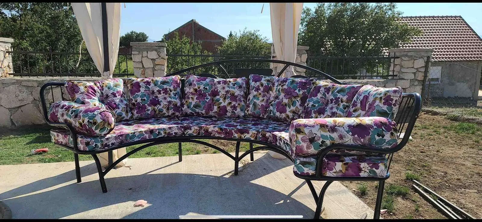 Yard with seating furniture under a canopy.