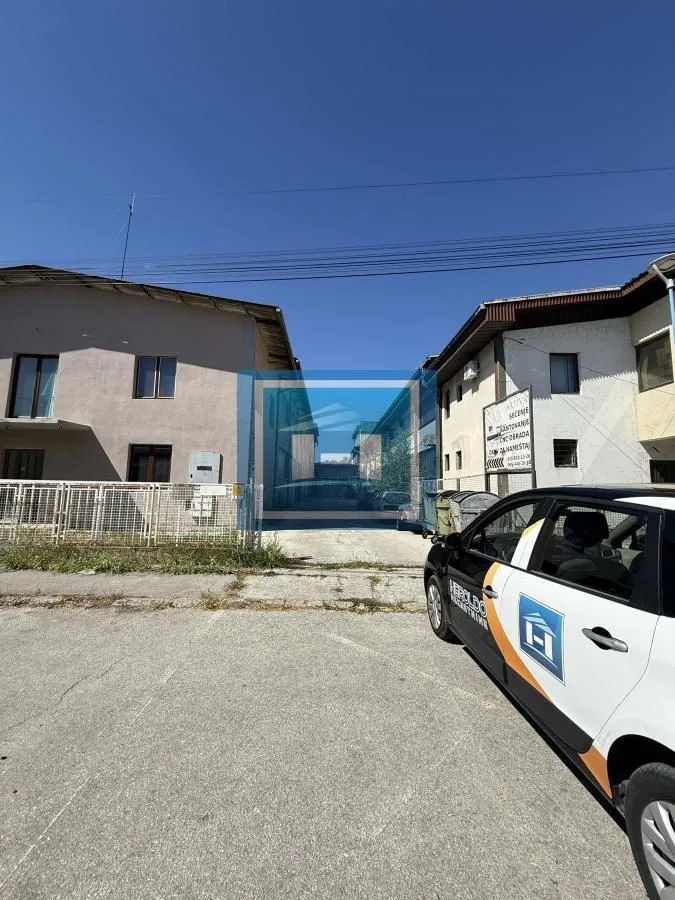 View of the exterior space with buildings and a parked car.