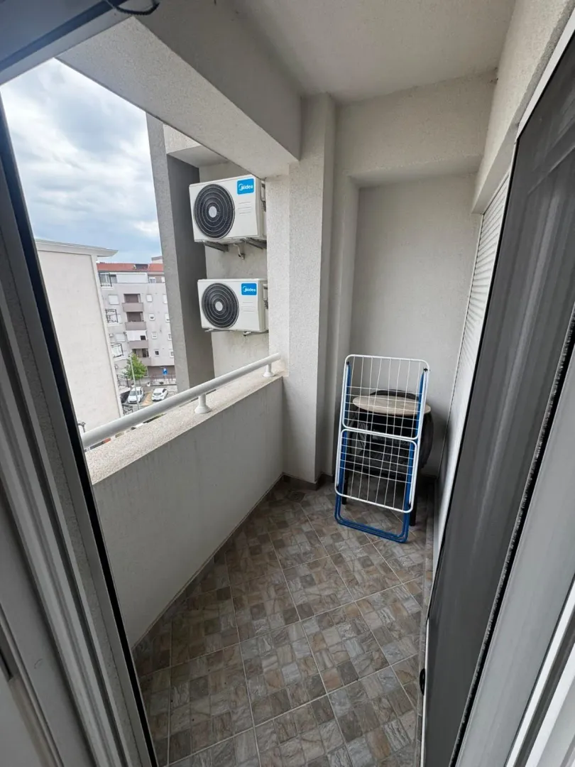 Small tiled balcony with air conditioning units and a clothes drying rack.