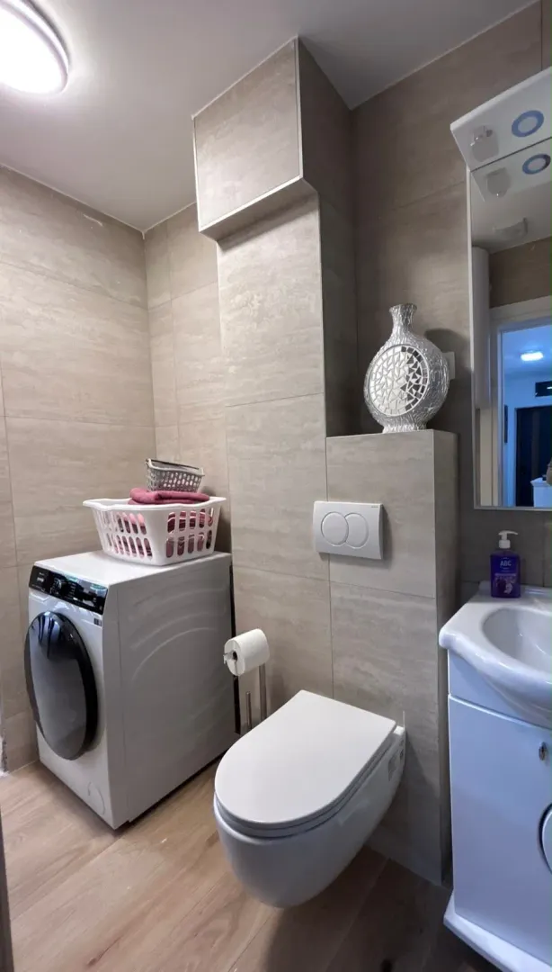 Modern equipped bathroom with a washing machine and beige tone sanitary ware.