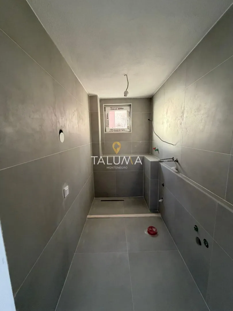 Bathroom under renovation tiled with grey tiles and prepared plumbing installations.