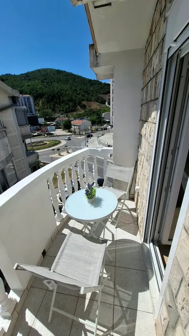 Small furnished balcony with seating furniture and a view of the surroundings.