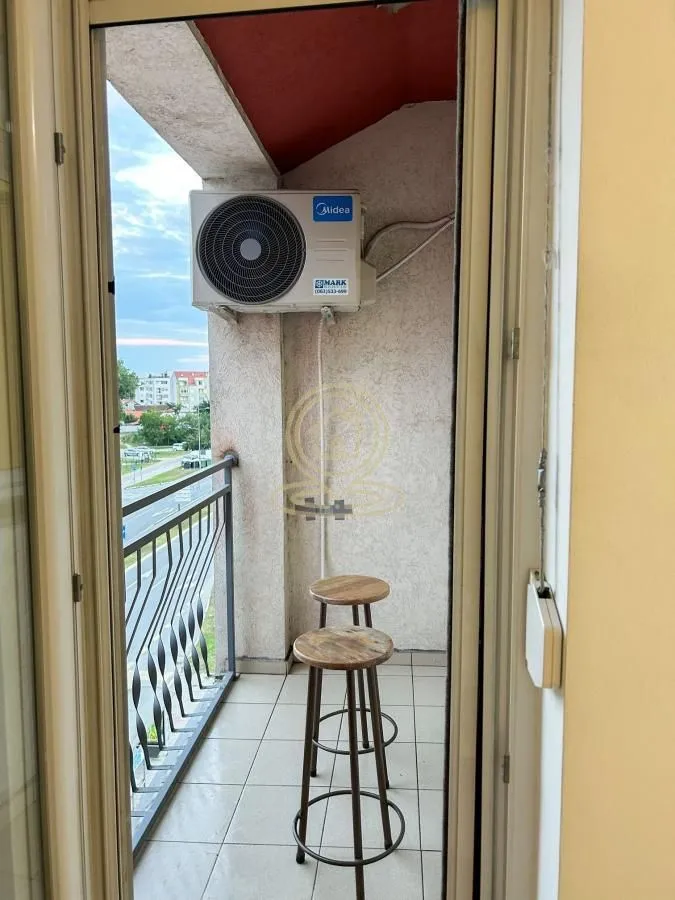 Manji balkon sa stolicama i spoljnom jedinicom klima uređaja.