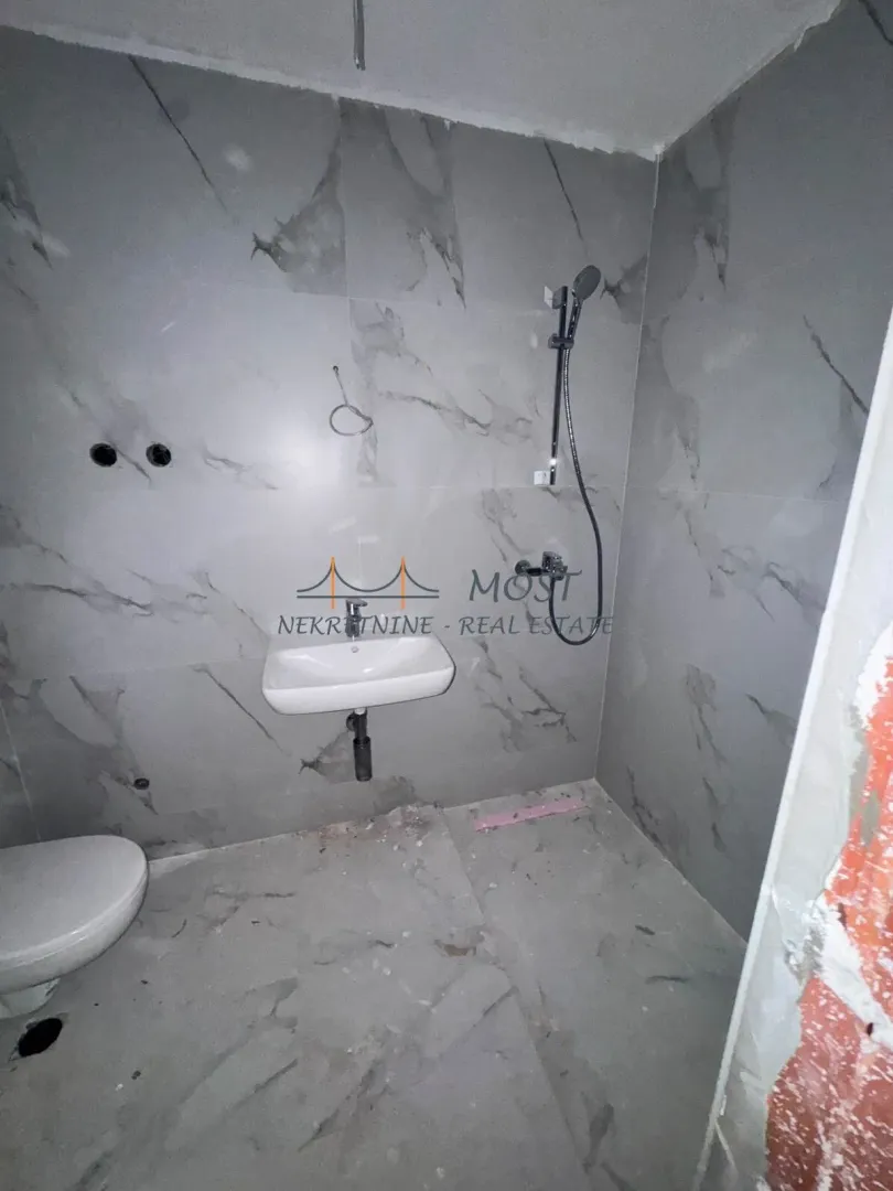 Nekoršćeno kupatilo sa sivim pločicama i sanitarijama.