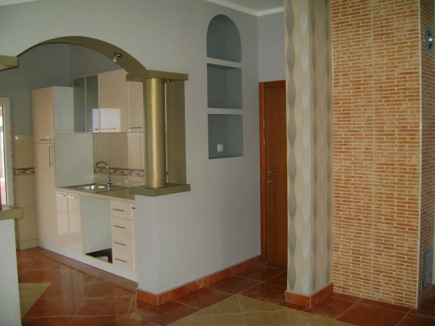 A kitchen with light-colored cabinets and a decorative arch.