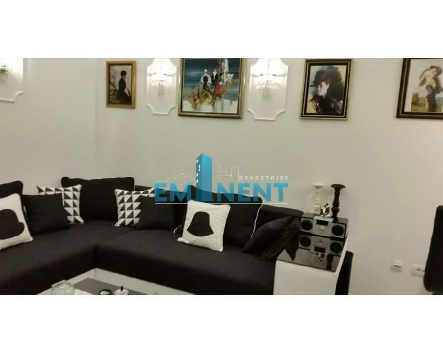 Living room with a black corner sofa and paintings on the wall.