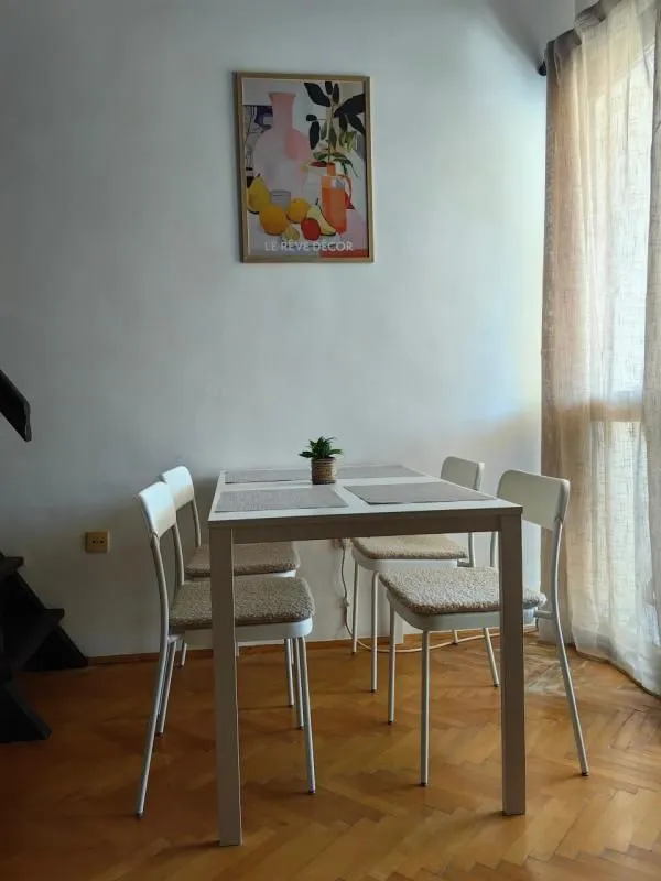 Trpezarijski sto sa četiri stolice pored prozora.