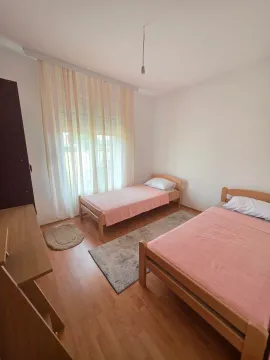 Bright bedroom with two wooden beds and a large window. - image 8