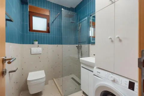 Modernly equipped bathroom with a shower cabin, washbasin, and washing machine. - image 12