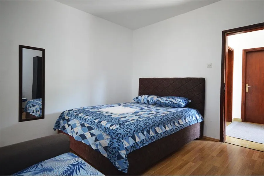 Furnished bedroom with a double bed and a wall mirror.