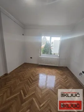 Prazna soba sa parketom i radijatorom ispod prozora. - image 6