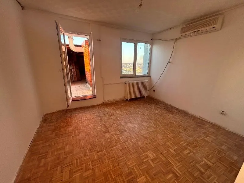 Prazna soba sa parketom, klima uređajem i izlazom na terasu.