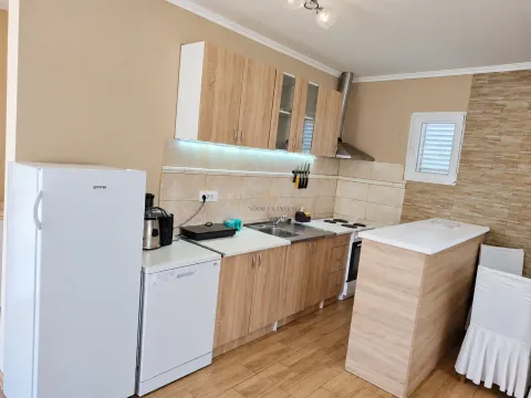 Equipped kitchen with wooden cabinets, white goods, and a breakfast bar. - image 8