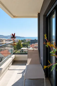 Natkriveni balkon sa ležaljkom i pogledom na grad i more. - image 9