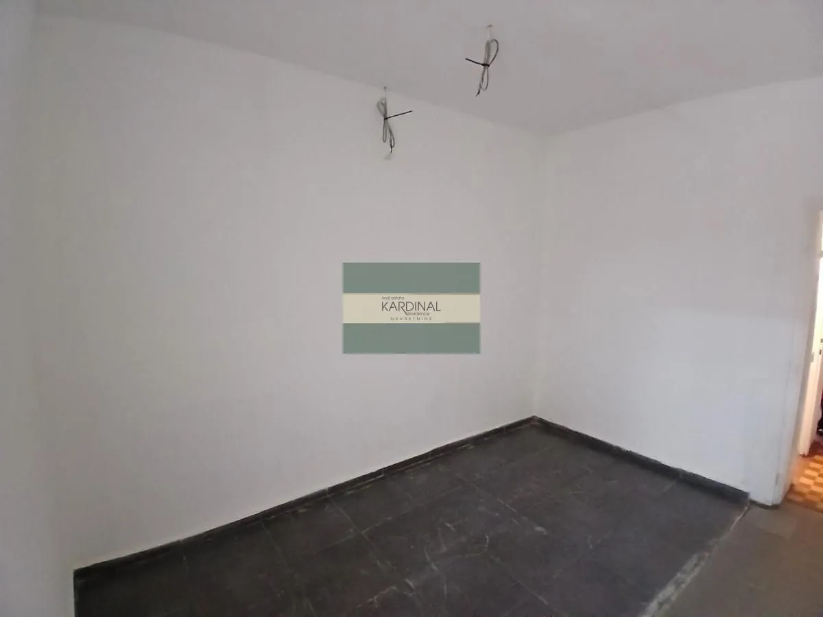 Empty room with white walls and dark floor tiles.