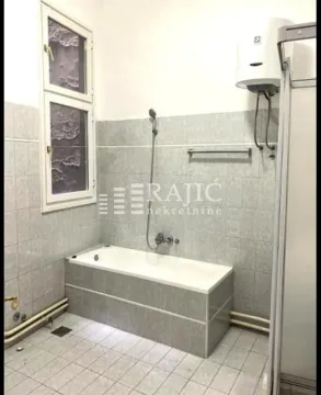 Smaller bathroom with a bathtub, tiles, and a water heater. - image 9