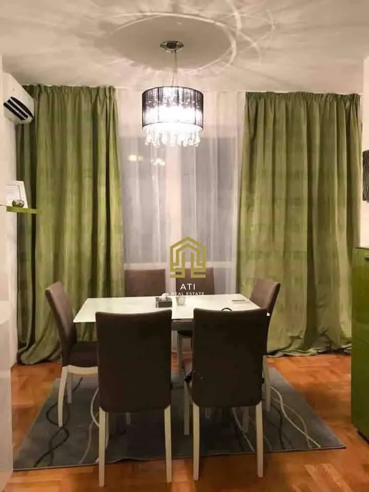 Trpezarija sa stolom, stolicama i zelenim zavjesama.