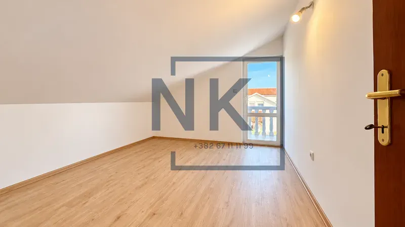 Empty attic room with laminate flooring and access to a terrace.