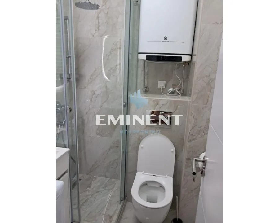 Small bathroom with a shower cabin, toilet, and water heater.