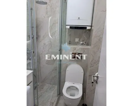 Small bathroom with a shower cabin, toilet, and water heater. - image 2