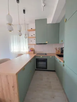 Moderna kuhinja sa zelenim elementima i drvenom radnom površinom. - image 3