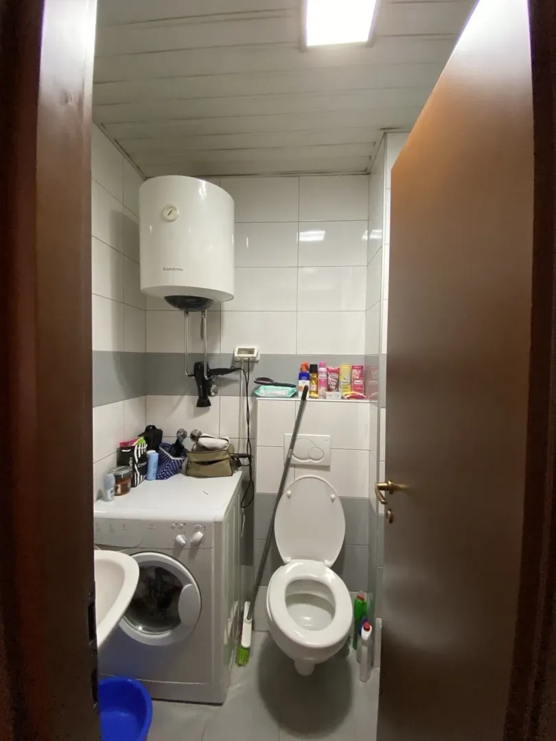 A small functional bathroom with a washing machine and water heater.