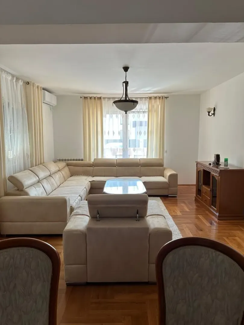 Spacious living room with a corner sofa and dining table in the foreground.