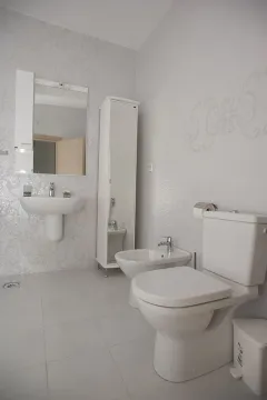Svijetlo kupatilo sa bijelim pločicama, sanitarijama i bideom. - image 5