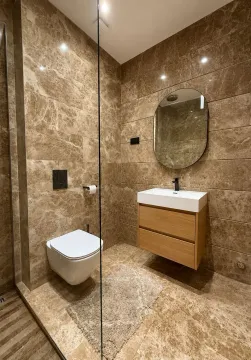 Moderne kupatilo obloženo keramičkim pločicama u boji mermera sa konzolnom šoljom i umivaonikom. - image 10