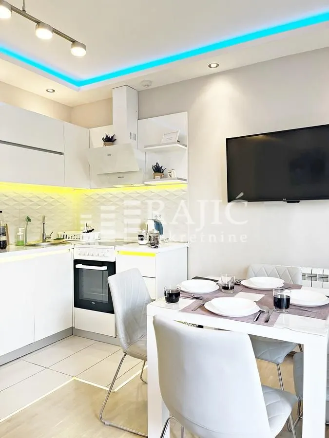 Modern white kitchen with a dining area and built-in appliances.