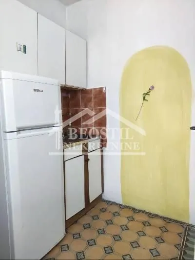Small kitchen with a refrigerator, white cabinets, and patterned floor tiles.