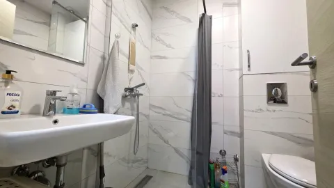 Modern bathroom equipped with white marble tiles, a sink, and a shower cabin. - image 10