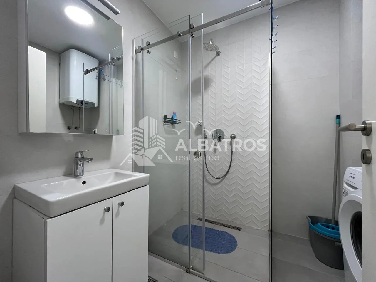 Modern bathroom equipped with a shower cabin, washbasin, and washing machine.