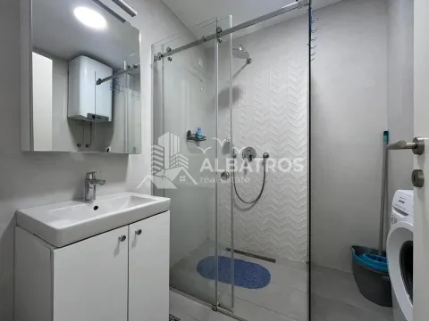 Modern bathroom equipped with a shower cabin, washbasin, and washing machine. - image 11