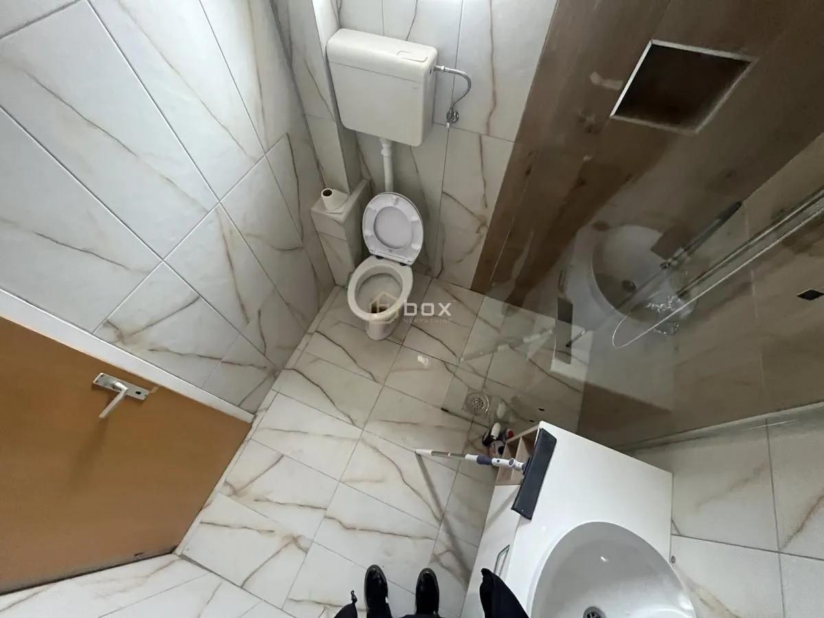Top-down view of the bathroom with a toilet, walk-in shower, and washbasin.