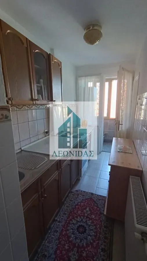 Smaller kitchen with wooden cabinets and access to the terrace.