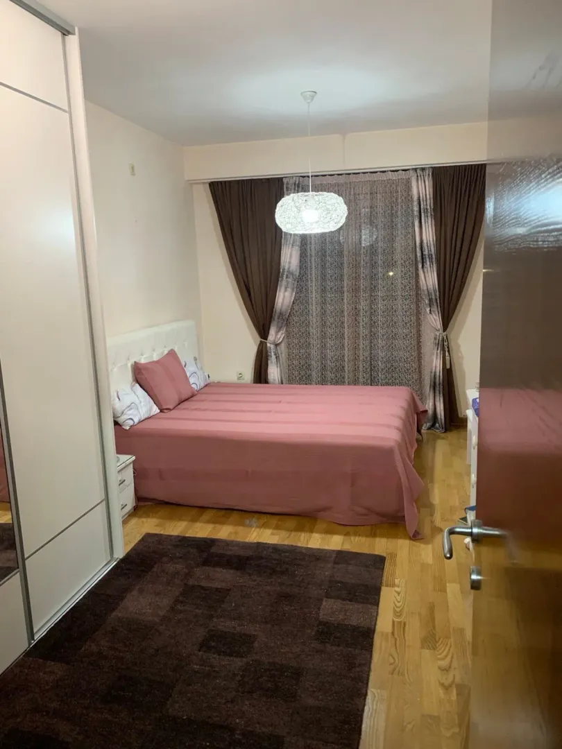 Namještena spavaća soba sa bračnim krevetom, garderoberom i prozorom.