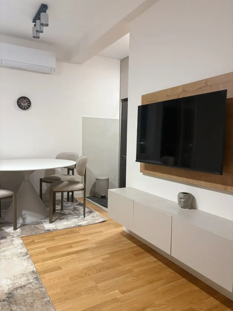 Living room with a TV, dining table and air conditioning.