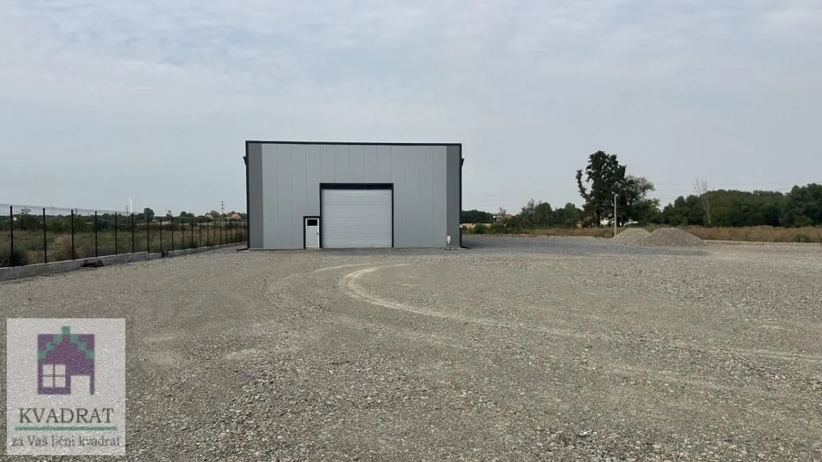 Exterior view of an industrial building with a large gravel-paved yard.