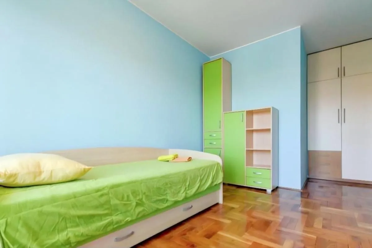 Dječja soba sa krevetom, plakarom i radnim elementima u plavim i zelenim tonovima.