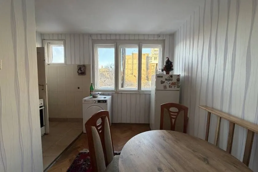 Manja kuhinja sa trpezarijskim stolom i stolicama, frižiderom i mašinom za veš.
