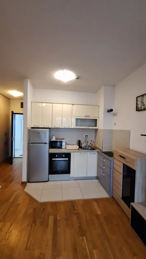 Small kitchen with white cabinets and wooden flooring.