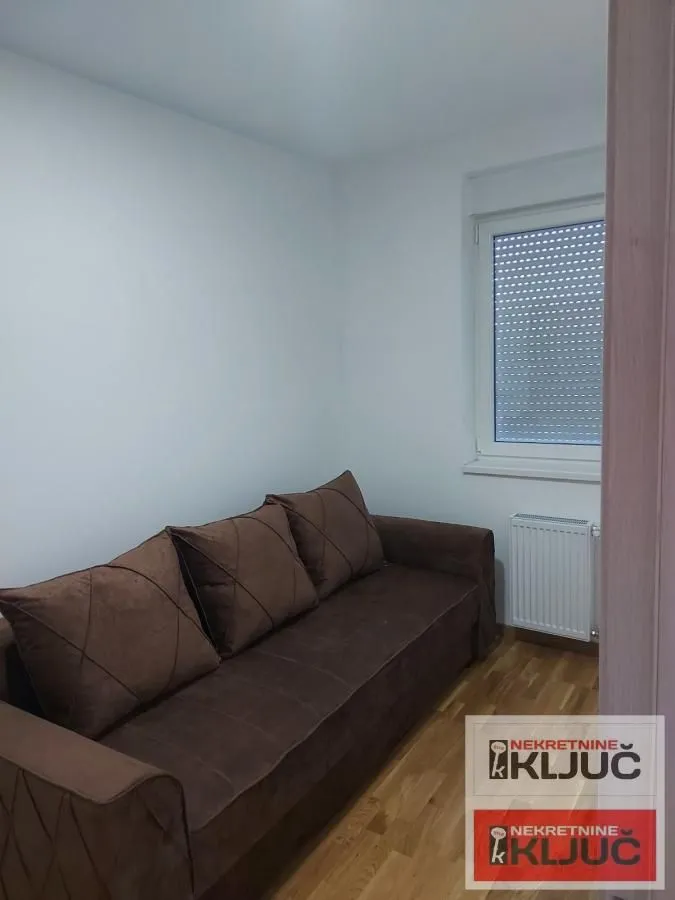 Manja soba sa bračnim krevetom i prozorom.